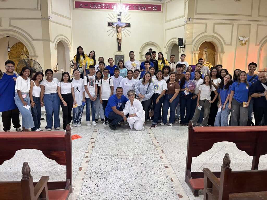 Un grupo numeroso de jóvenes posa con la Dra. Maribel Orozco en el interior de la Iglesia María Rosa, bajo el letrero «Cristo es mi vida».