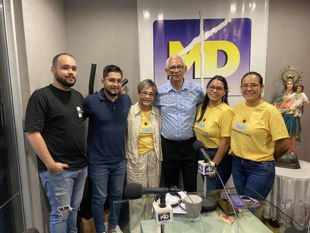 El equipo de la fundación posa en la cabina de Minuto de Dios, junto a los micrófonos y bajo el logo de la emisora.