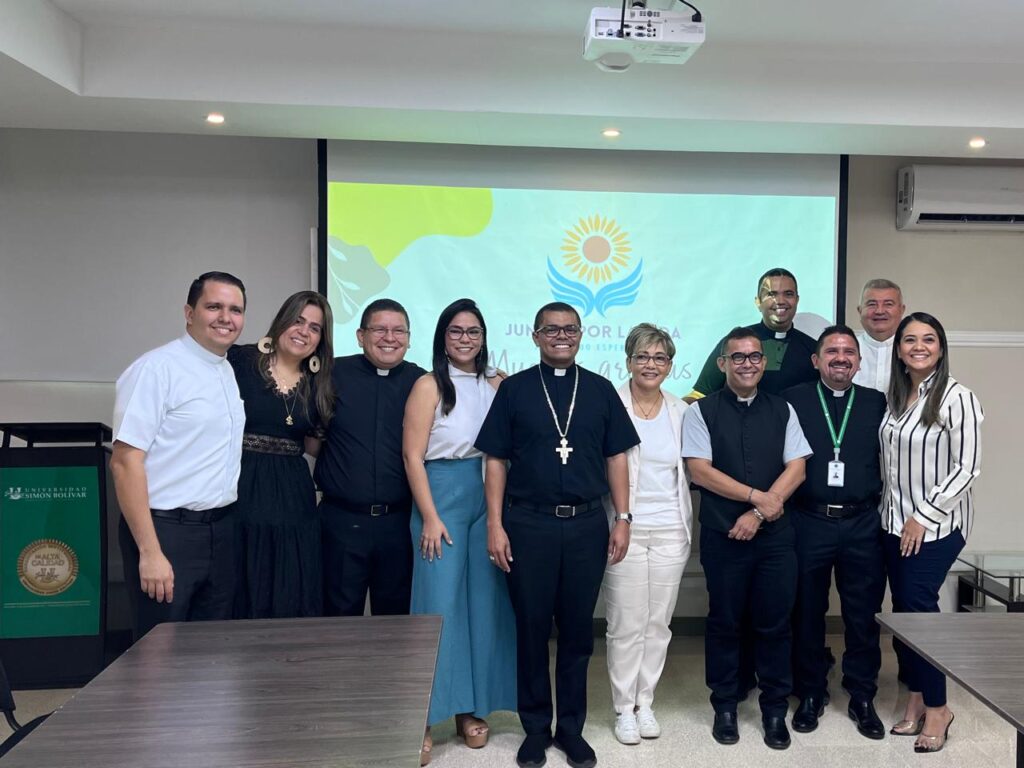 Sacerdotes y equipo pastoral posan junto a la Dra. Maribel Orozco frente a la pantalla con el logo de la fundación.