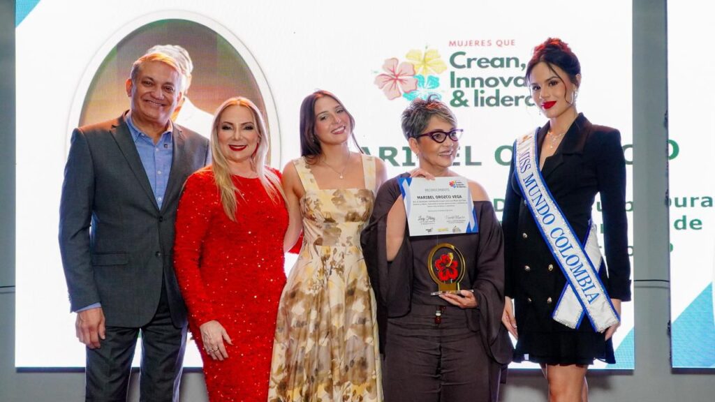 La Dra. Maribel Orozco Vega sostiene el diploma y el trofeo del reconocimiento «Mujeres que Crean, Innovan y Lideran», acompañada en el escenario.