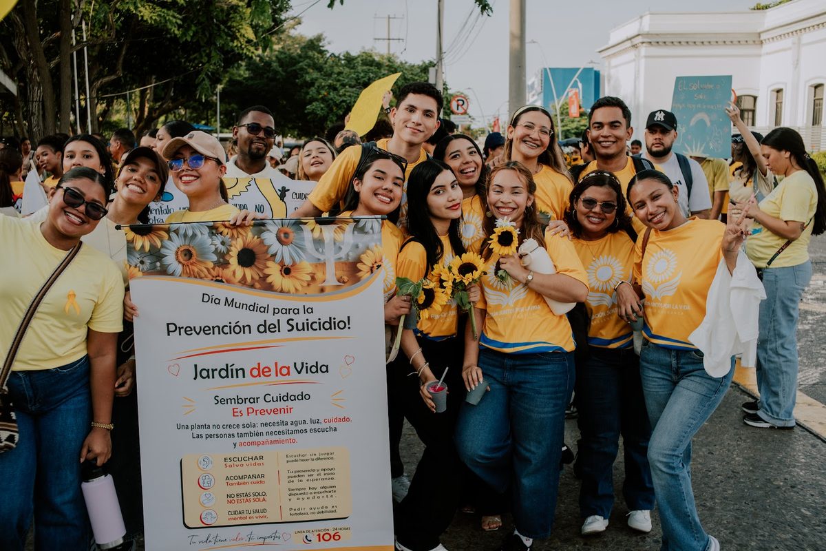 Grupo posando con una pancarta de prevención del suicidio.