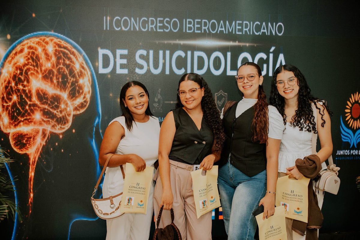 Grupo de asistentes posando frente al mural del II Congreso Iberoamericano de Suicidología.
