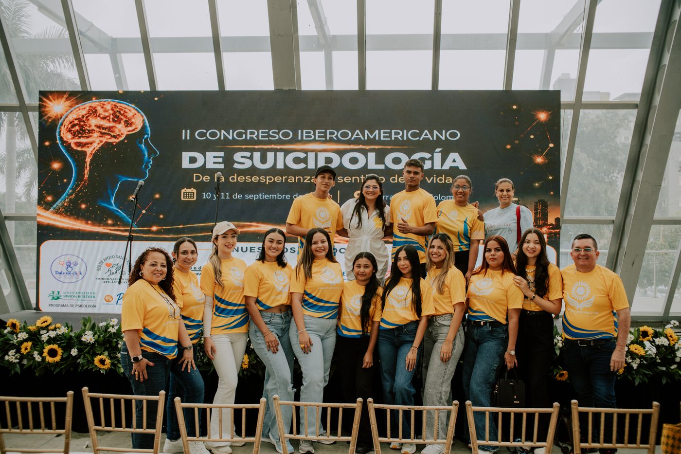 Grupo del equipo anfitrión en la tarima adornada con girasoles.